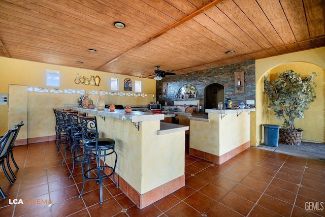 kitchen featuring a ceiling fan, wooden ceiling, dark tile patterned floors, and a peninsula