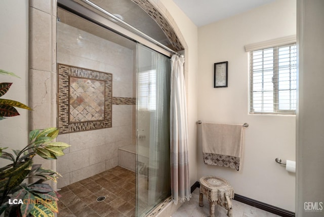 bathroom with baseboards and a shower stall
