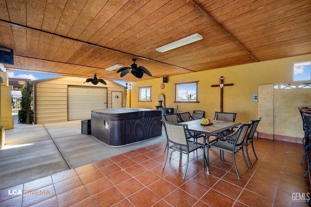 view of patio / terrace featuring a hot tub, an outbuilding, outdoor dining area, and a ceiling fan