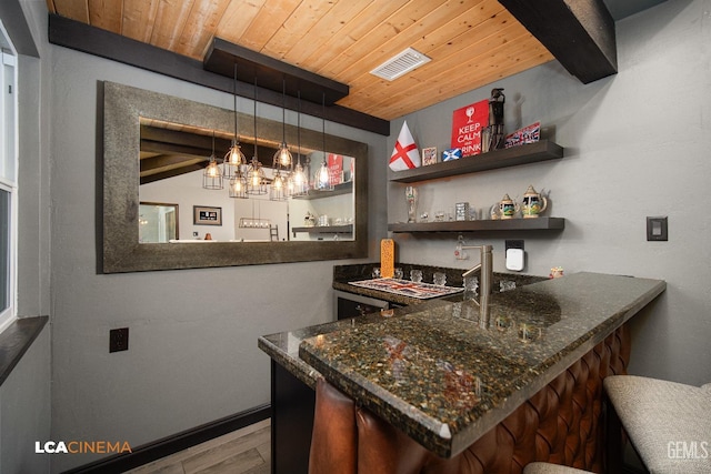 bar featuring hardwood / wood-style floors, dark stone counters, hanging light fixtures, beamed ceiling, and wood ceiling