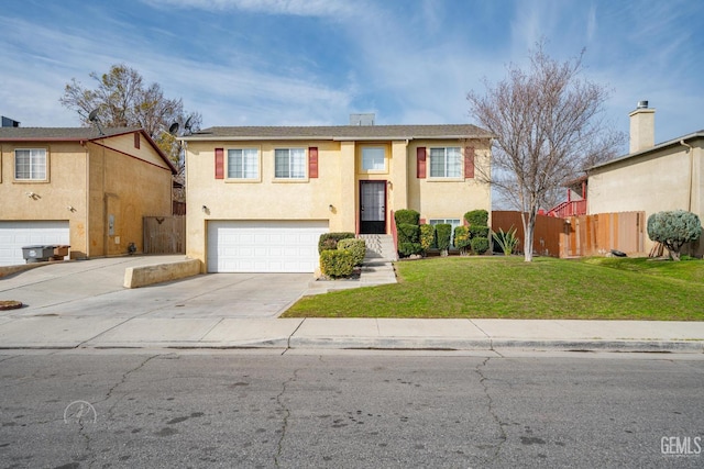 raised ranch featuring an attached garage, fence, concrete driveway, stucco siding, and a front yard