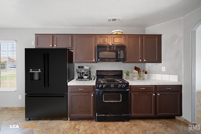 3400 Tori Lorene Ave, Bakersfield, CA 93313 - kitchen with tile counters, black appliances, arched walkways, and dark brown cabinets