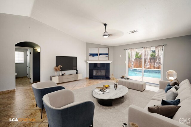 3400 Tori Lorene Ave, Bakersfield, CA 93313 - living room featuring vaulted ceiling, arched walkways, a ceiling fan, light tile patterned flooring, and a tiled fireplace