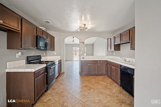 3400 Tori Lorene Ave, Bakersfield, CA 93313 - kitchen with arched walkways, black appliances, tile countertops, a peninsula, and a chandelier