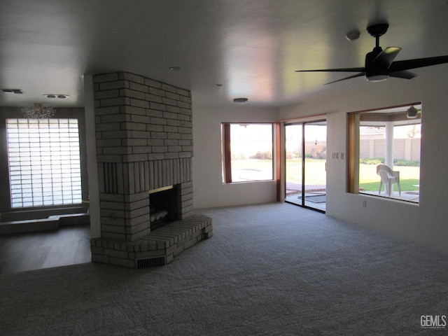 unfurnished living room featuring ceiling fan, a fireplace, a healthy amount of sunlight, and carpet