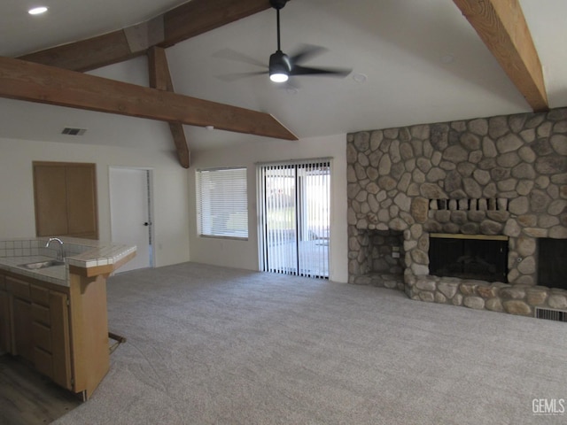 living room featuring light carpet, sink, a fireplace, and vaulted ceiling with beams