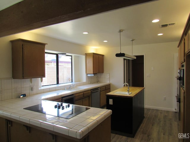 kitchen featuring a kitchen island with sink, tile countertops, backsplash, and black appliances