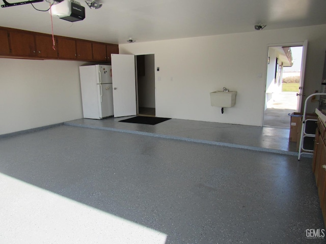 garage with white refrigerator, a garage door opener, and sink