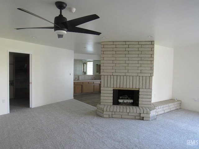 unfurnished living room featuring ceiling fan, carpet flooring, and a fireplace