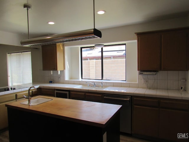 kitchen with tasteful backsplash, sink, tile counters, and a center island