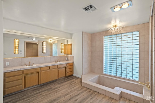 7108 Luke Ave, Bakersfield, CA 93308 - bathroom with a chandelier, double vanity, wood finished floors, and decorative backsplash