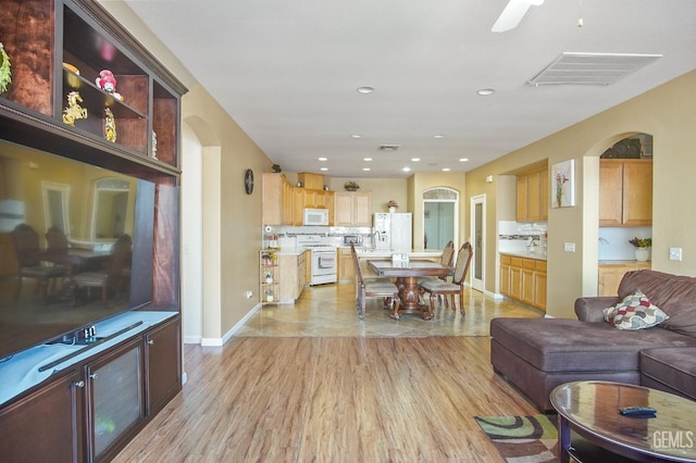 living room with light wood-style flooring, visible vents, baseboards, and recessed lighting