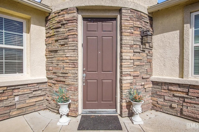 entrance to property with stone siding and stucco siding