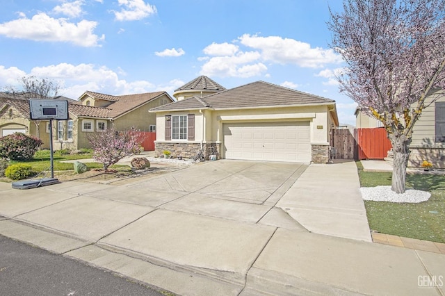 view of front of property featuring a garage, stone siding, driveway, and fence