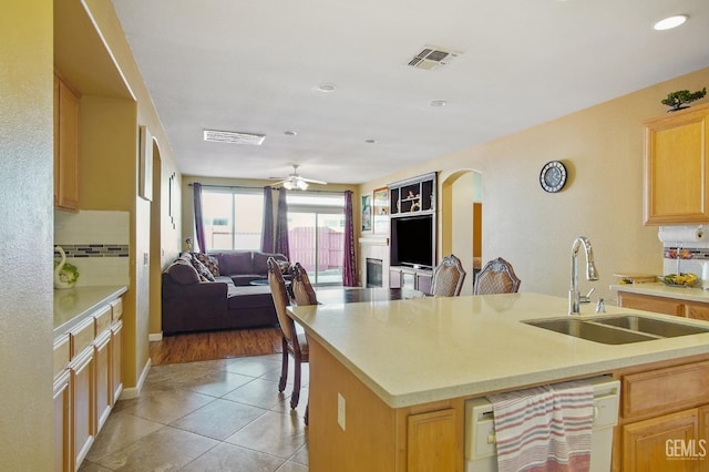 kitchen featuring arched walkways, visible vents, dishwasher, open floor plan, and a sink