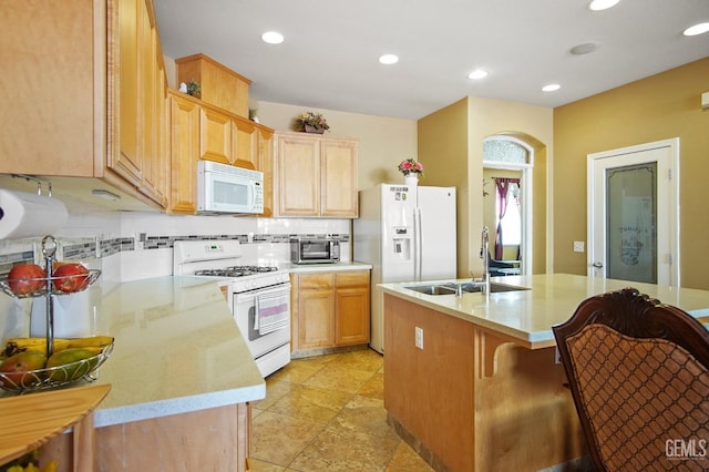 kitchen with white appliances, decorative backsplash, light countertops, and a sink