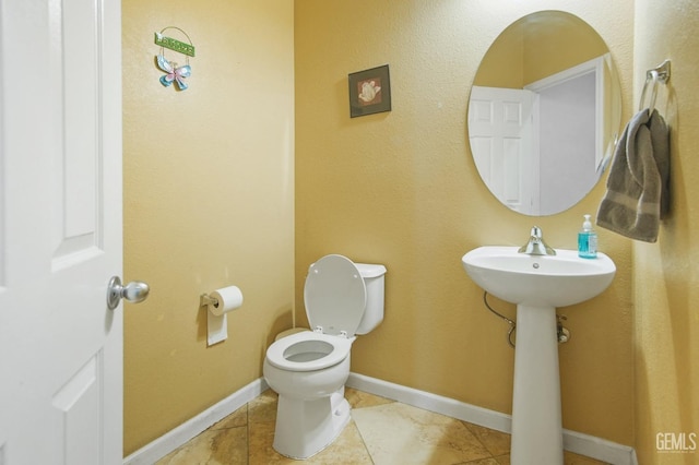 bathroom with tile patterned floors, toilet, and baseboards