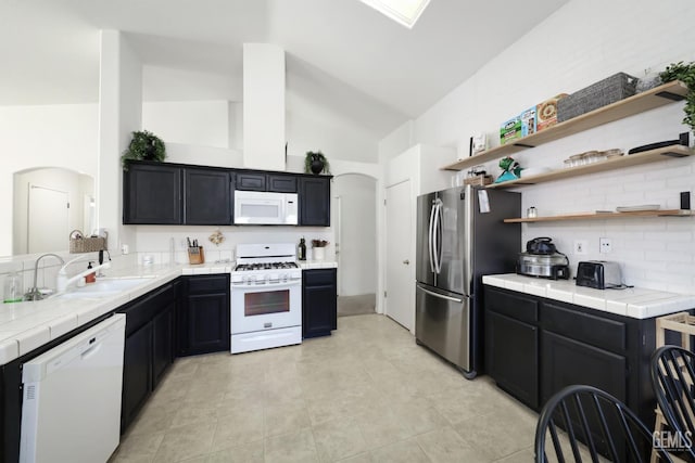 4811 Council Bluffs Ct, Bakersfield, CA 93311 - kitchen featuring white appliances, arched walkways, dark cabinets, decorative backsplash, and high vaulted ceiling