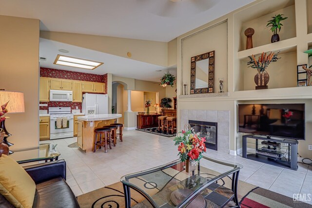 502 Lewisham St, Bakersfield, CA 93311 - living room featuring arched walkways, light tile patterned floors, a tiled fireplace, and lofted ceiling