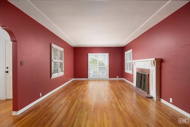 unfurnished living room featuring a brick fireplace and light wood-type flooring