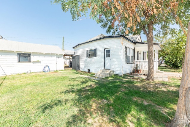 rear view of property featuring a yard and an outdoor structure