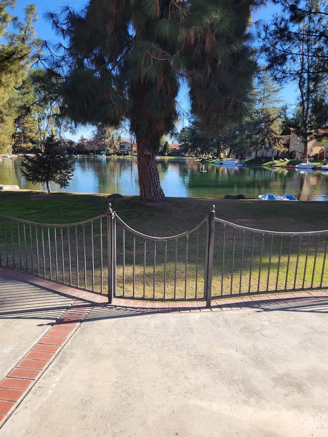 view of gate with a lawn and a water view