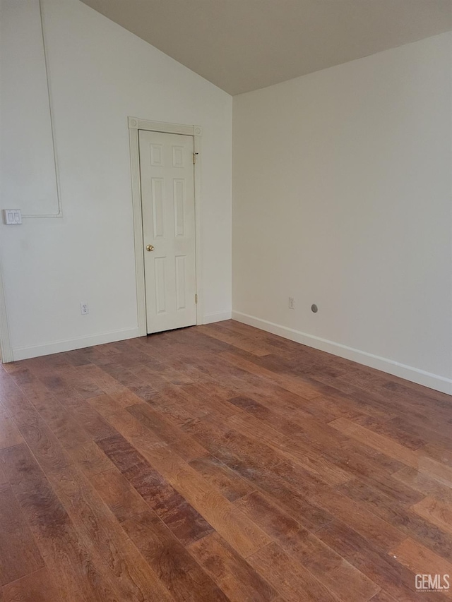 spare room featuring vaulted ceiling and dark wood-type flooring