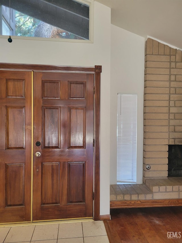 foyer entrance featuring lofted ceiling, a fireplace, and light tile patterned flooring