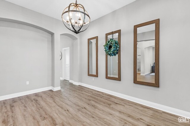 spare room with light hardwood / wood-style flooring and a chandelier