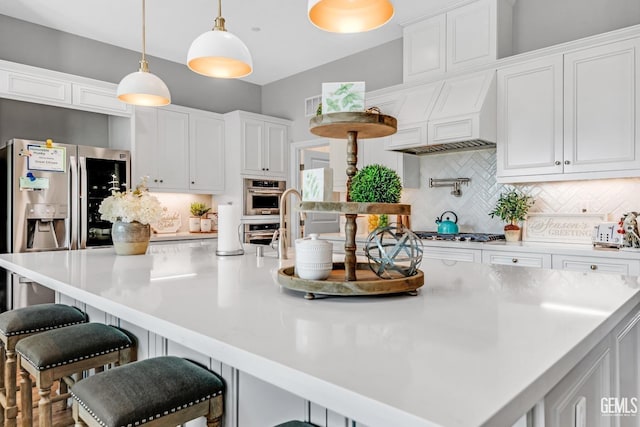 kitchen featuring a large island with sink, backsplash, white cabinetry, and pendant lighting