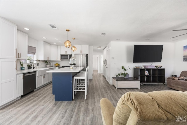 21633 Golden Hills Blvd, Tehachapi, CA 93561 - kitchen with appliances with stainless steel finishes, open floor plan, white cabinets, a center island, and a kitchen breakfast bar