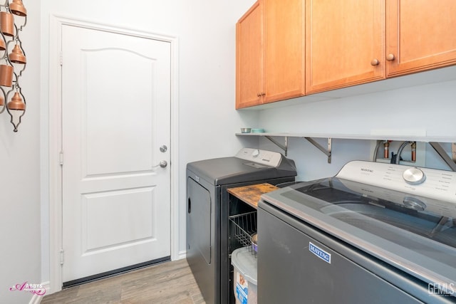 washroom with washer and clothes dryer, cabinets, and light wood-type flooring