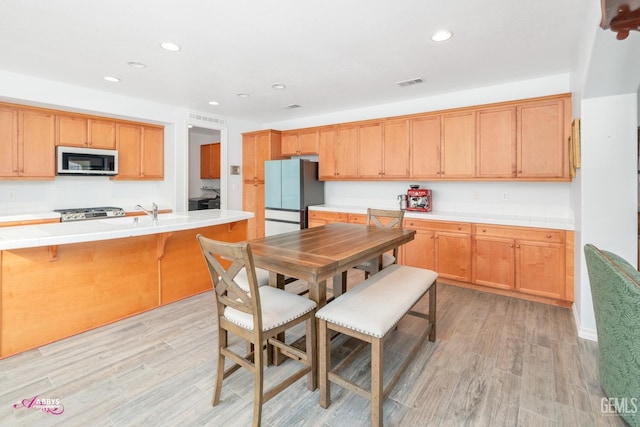 kitchen featuring range, stainless steel refrigerator, and light hardwood / wood-style flooring