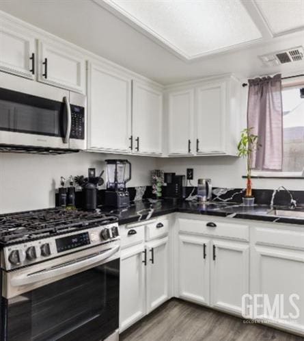 337 Cesar Chavez Ln, Delano, CA 93215 - kitchen with stainless steel appliances, a sink, light wood-style floors, white cabinetry, and dark countertops