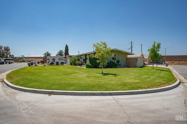 single story home with a storage shed, an outbuilding, a front yard, and stucco siding