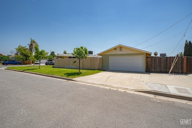single story home featuring a detached garage, fence, and a front yard