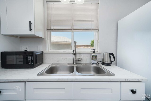 kitchen featuring white cabinets, black microwave, and a sink