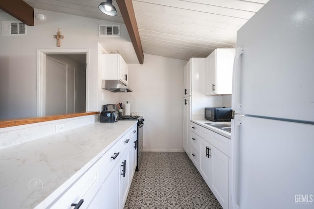 kitchen with visible vents, black microwave, gas stove, freestanding refrigerator, and under cabinet range hood