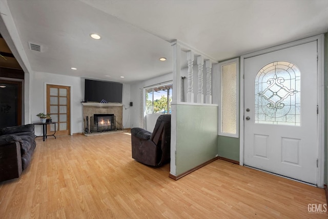 foyer with light wood finished floors, recessed lighting, visible vents, and a glass covered fireplace