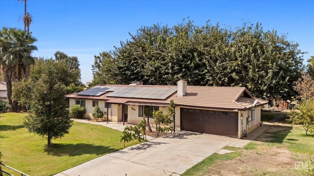 single story home with solar panels, concrete driveway, a front yard, a garage, and a tiled roof