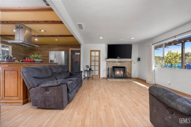 living room featuring light wood-type flooring, visible vents, a lit fireplace, and recessed lighting