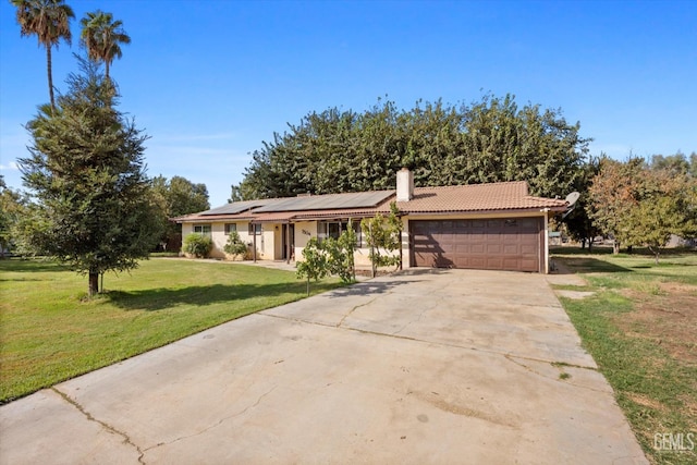 ranch-style home with a chimney, solar panels, concrete driveway, an attached garage, and a front lawn