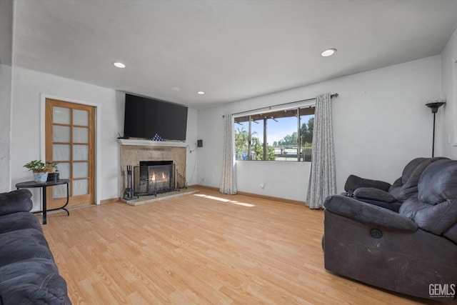 living area with baseboards, recessed lighting, a tile fireplace, and light wood-style floors