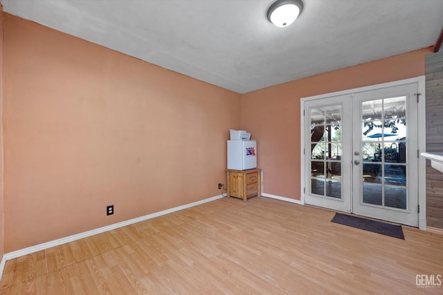 unfurnished room featuring baseboards, wood finished floors, and french doors