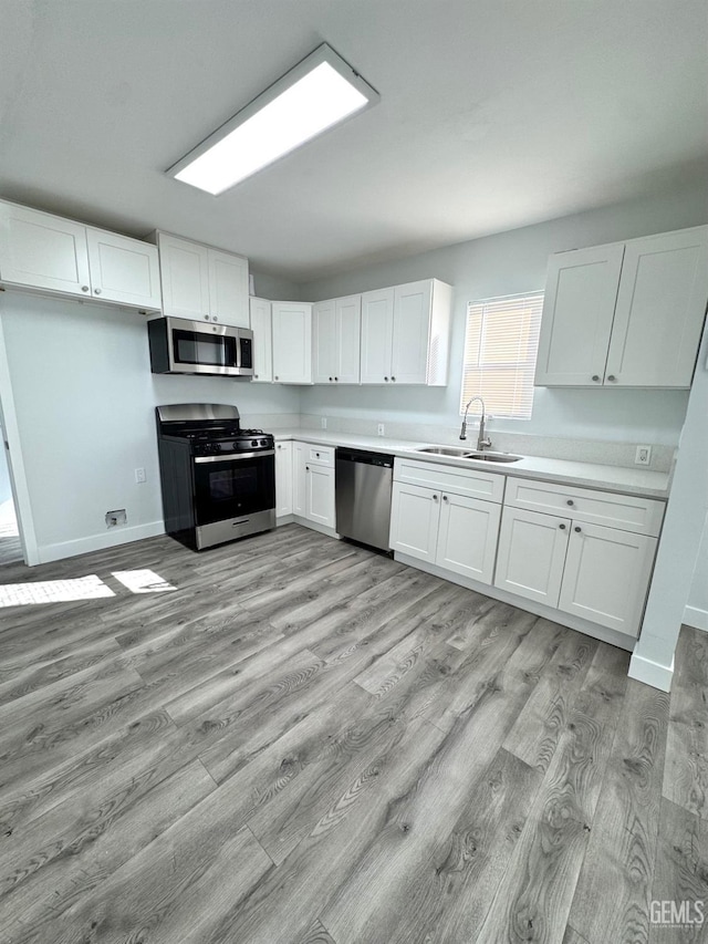 kitchen featuring sink, light hardwood / wood-style flooring, stainless steel appliances, and white cabinets