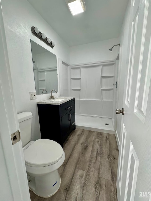 bathroom with a shower, hardwood / wood-style floors, vanity, and toilet