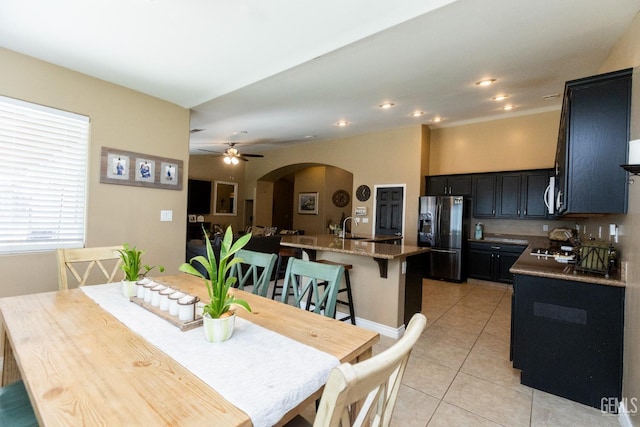 dining space with ceiling fan, light tile patterned floors, and sink