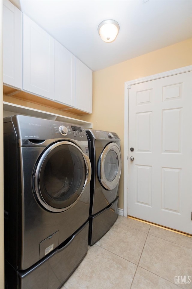 laundry area featuring cabinets, light tile patterned floors, and washing machine and clothes dryer