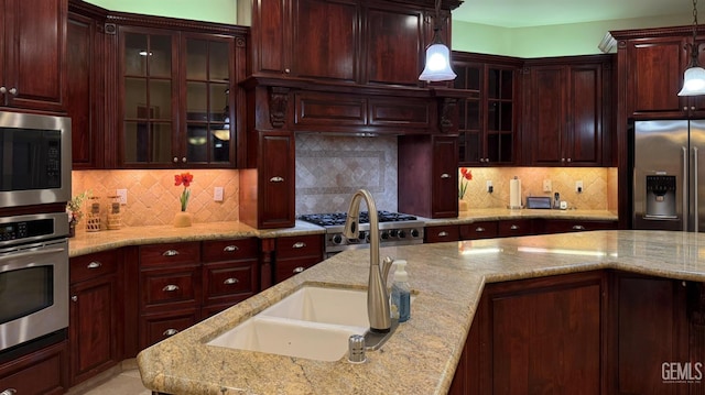 3006 Springbank Ct, Bakersfield, CA 93311 - kitchen featuring appliances with stainless steel finishes, reddish brown cabinets, decorative light fixtures, and backsplash