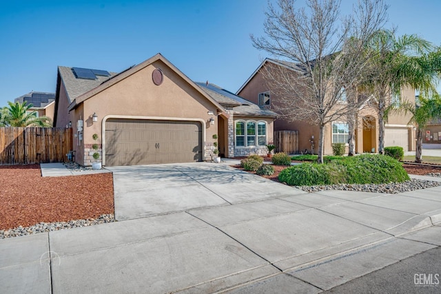 view of front facade featuring solar panels, stucco siding, concrete driveway, an attached garage, and fence